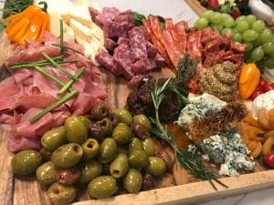 A charcuterie board featuring an assortment of meats, cheeses, olives, fruits, and honeycomb.