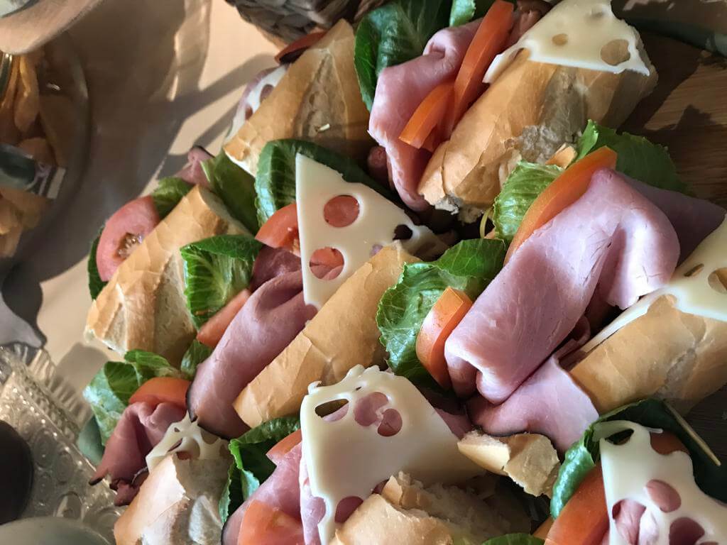 Platter of sandwiches with ham, cheese, lettuce, and tomato.