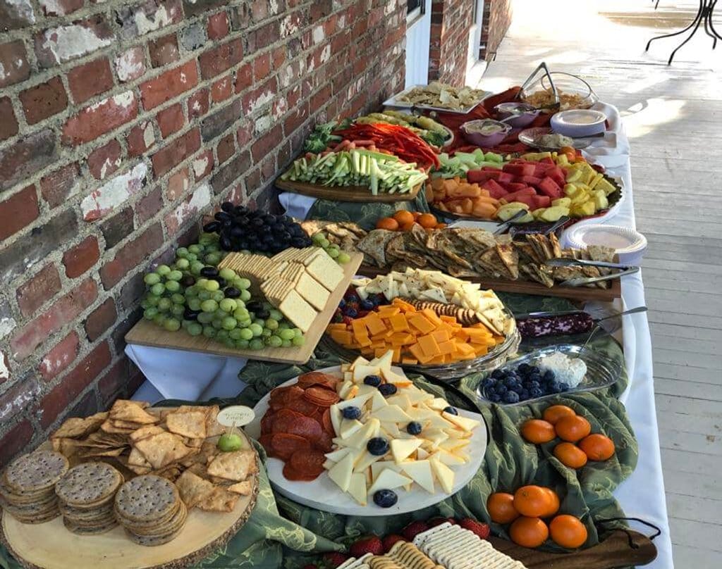 Appetizer table of cheese, crackers, pepperoni, grapes, clementines, dip, crudités, and chips