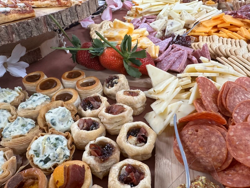 An assortment of cheeses, cold cuts, and appetizers arranged on a serving board.